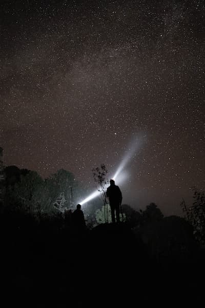 Dans l'obscurité, deux personnes avec des lampes frontales regardent vers les étoiles